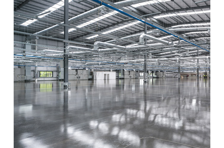 Im Bild ist eine moderne Industriehalle mit glänzendem grauen Boden zu sehen
