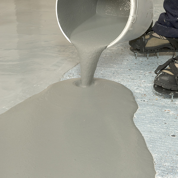 Im Bild wird Flowtop aus einem Eimer direkt auf den zu reparierenden Betonboden gegossen